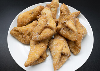 Pestiños on a white plate and black background