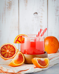 Sicilian blood orange on wooden background. Blood orange juice with ice and orange slice.