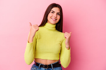 Young caucasian woman isolated on pink background raising both thumbs up, smiling and confident.