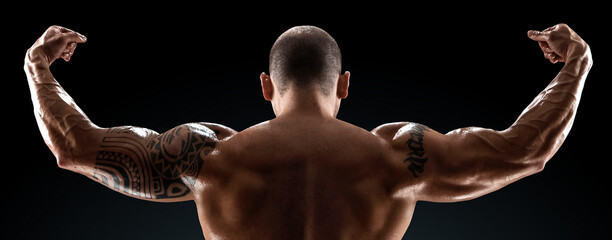 Male bodybuilder with light stubble with a naked torso posing against a dark background. The...