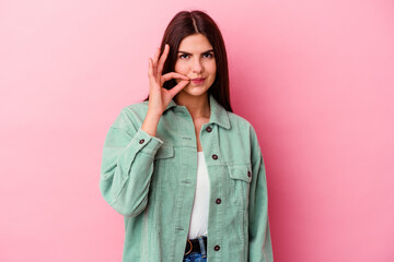 Young caucasian woman isolated on pink background with fingers on lips keeping a secret.