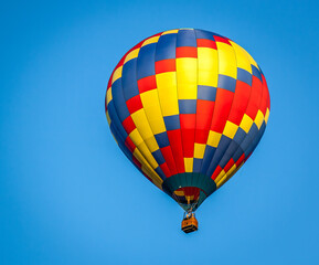 Closeup of a red, yellow and blue hot air balloon against a clear blue sky..  Flying over Wesley Chapel, near Tampa, Florida.