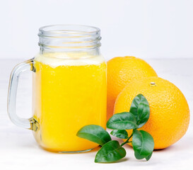 Orange juice and green leaves on a white background.A glass of orange juice and orange fruit. Healthy food. Vegan food