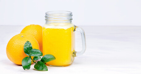 Orange juice and green leaves on a white background.A glass of orange juice and orange fruit. Healthy food. Vegan food
