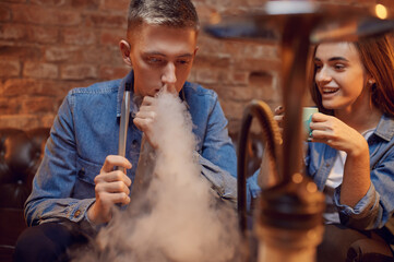 Young love couple relax in hookah bar, hooka smoke