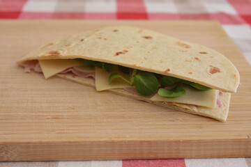 close up of Italian piadina romagnola with cheese, ham and salad, healthy food lifestyle, traditional