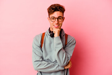 Young student man isolated on pink background smiling happy and confident, touching chin with hand.