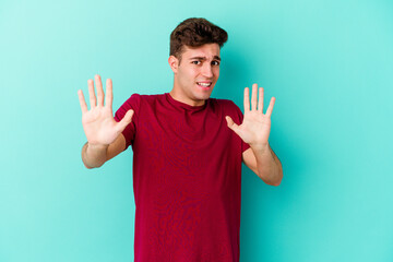 Young caucasian man isolated on blue background rejecting someone showing a gesture of disgust.