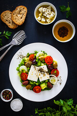 Fresh Greek salad - feta cheese, tomatoes, cucumber, lettuce, black olives and onion on wooden table
