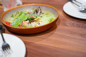 fresh green vegetable salad with corn carrot lettuce and tomato on dish and wooden table with fork and spoon for diet and clean food or vegetarian with space