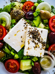 Fresh Greek salad - feta cheese, tomatoes, cucumber, lettuce, black olives and onion on wooden...