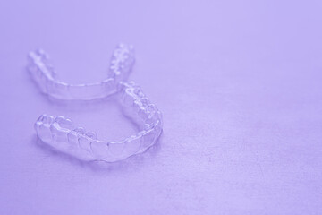 Invisible aligner teeth retainers on a purple background