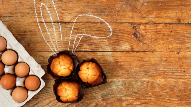 Homemade muffin with painted rabbit ears. Muffin and eggs on a wooden