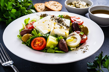 Fresh Greek salad - feta cheese, tomatoes, cucumber, lettuce, black olives and onion on wooden table
