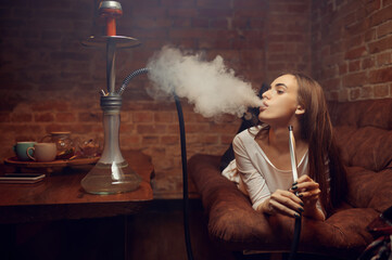 Young woman lying on sofa and smokes hookah in bar © Nomad_Soul