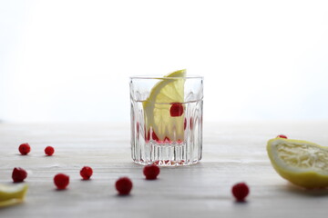 Short drinking glasses with cold vodka, lemon, cranberries on white background