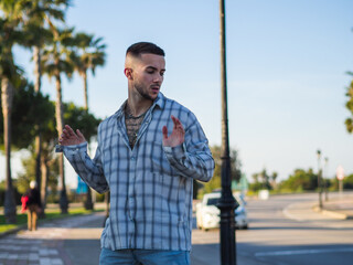 Hombre joven posando en una calle con palmeras durante el verano