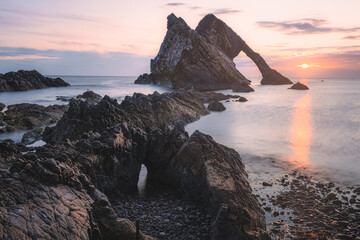 Beautiful dramatic sescape scenery at sunrise or sunset of Bow Fiddle Rock sea arch on the rocky...