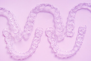 Invisible dental teeth brackets tooth aligners on pink background. Plastic braces dentistry...