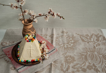 Easter composition. Traditional Orthodox cottage cheese dessert, sprigs of apricot blossoms in a ceramic vase on a linen tablecloth. Happy Easter Holidays. Free space.