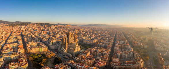 Aerial panorama drone shot of Barcelona center and coast in foggy morning golden hour in Spain winter