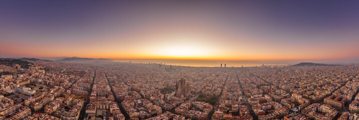 Aerial panorama drone shot of Barcelona with sunrise over sea horizon in Spain winter dawn