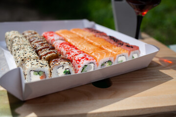 Delicious colorful sushi rolls and a glass of white in nature