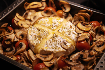 Camembert baked.Cheese with mushrooms and tomatoes in a baking sheet.Baked Camembert cheese with...