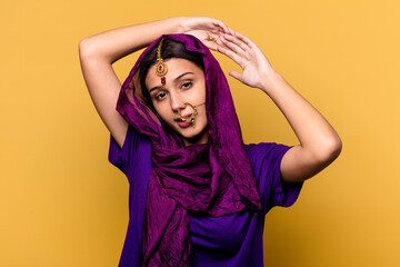 Young Indian woman wearing a traditional sari clothes isolated on yellow background stretching arms, relaxed position.