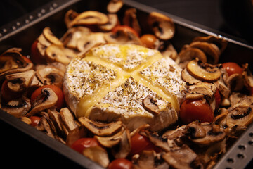 Camembert baked.Cheese with mushrooms and tomatoes in a baking sheet.Baked Camembert cheese with vegetables