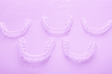 Invisible dental teeth brackets tooth aligners on pink background. Plastic braces dentistry retainers to straighten teeth.