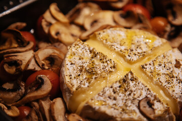 Camembert baked.Cheese with mushrooms and tomatoes in a baking sheet.Baked Camembert cheese with vegetables