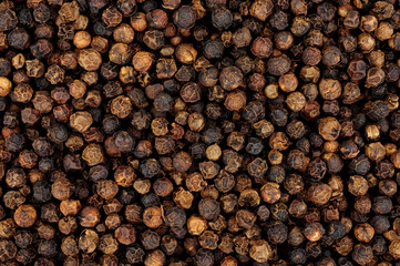 Whole dried black peppercorn spice seasoning background