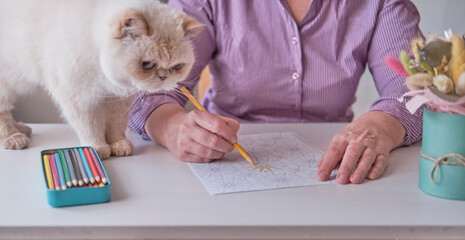 Elderly woman's hand painting an abstract pattern from adult coloring pages.