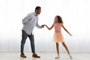 Black father and daughter dancing at home