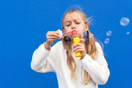 Funny girl blowing soap bubbles. High quality photo