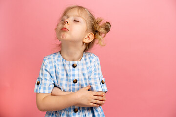 an offended little blonde on a pink isolated background with sincere emotions, a place for text....