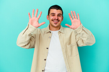 Naklejka premium Young caucasian man isolated on blue background showing number ten with hands.