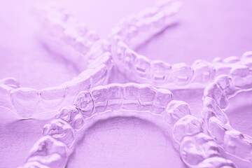 Invisible dental teeth brackets tooth aligners on pink background. Plastic braces dentistry retainers to straighten teeth.
