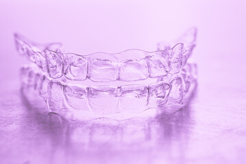Invisible dental teeth brackets tooth aligners on pink background. Plastic braces dentistry...