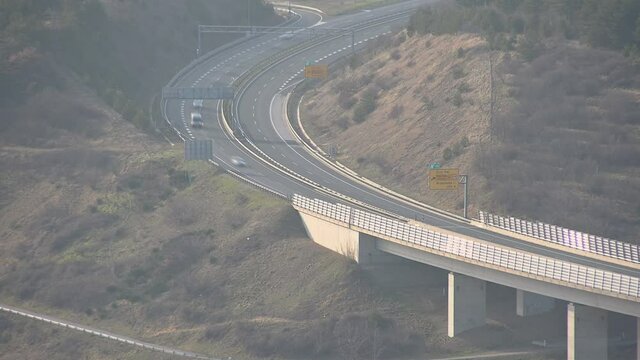 Sped up, time lapse elevated view of traffic on A1 highway and Crni Kal viaduct. Vehicles traveling on motorway. Aerial view of curved road. Static shot