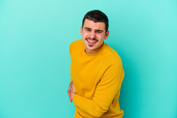 Young caucasian man isolated on blue background having a liver pain, stomach ache.