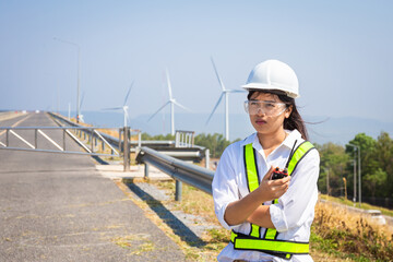 Asian woman engineers are using walkie-talkies outdoors on site power plant energy wind turbines
