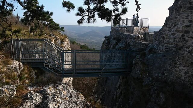Small bridge in Castle of San Sergio in Slovenia. Sightseeing point at castle ruins. The fortress of Crni Kal was noted in the 11th century. Couple standing on platform. Tilt up, wide angle