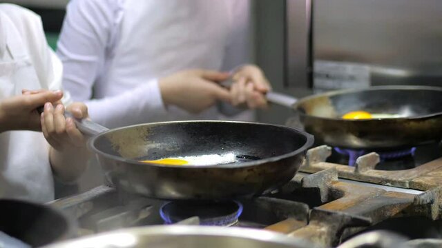 Kids learning how to cook eggs in a cooking class in restaurant kitchen