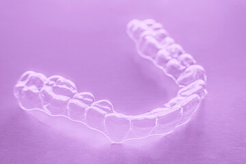 Invisible aligner teeth retainers on a purple background