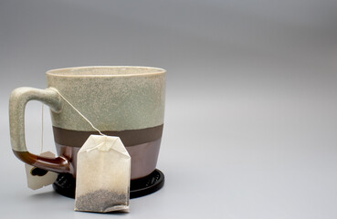 Ceramic mug with tea bag upright and string over the handle with blank background