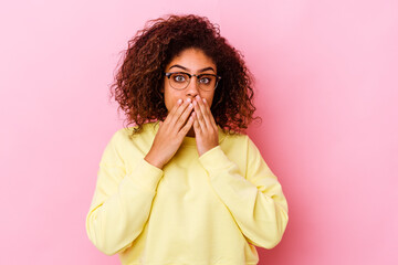 Young african american woman isolated on pink background shocked covering mouth with hands.