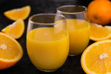 Two glasses with orange juice on a black background.
Close-up.