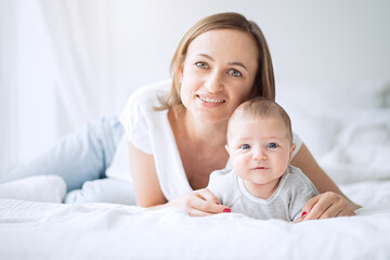 Portrait of a beautiful mother smiling with her 3 month old baby in bedroom     